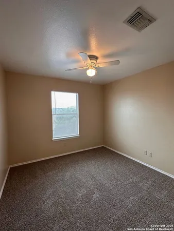 an empty room with a window and a fan