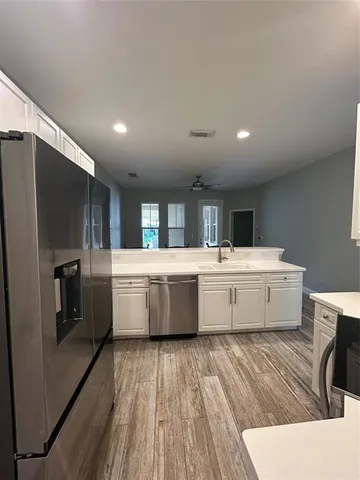 a large white kitchen with a large counter top space stainless steel appliances and windows