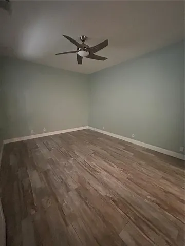 an empty room with wooden floor a ceiling fan and a window