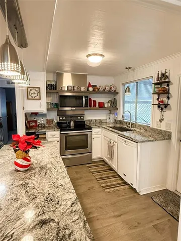 a kitchen with stainless steel appliances kitchen island granite countertop a stove and cabinets