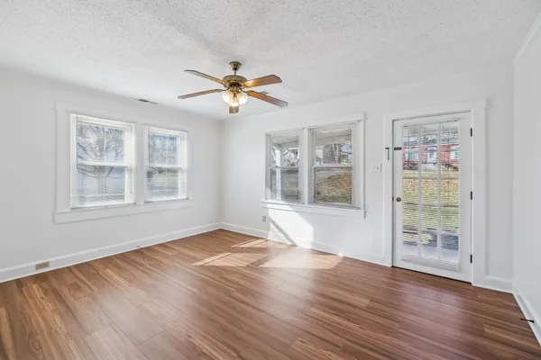 a view of an empty room with a window and wooden floor