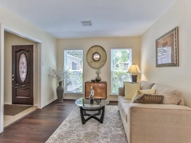 a living room with furniture a rug a wall painting and a window