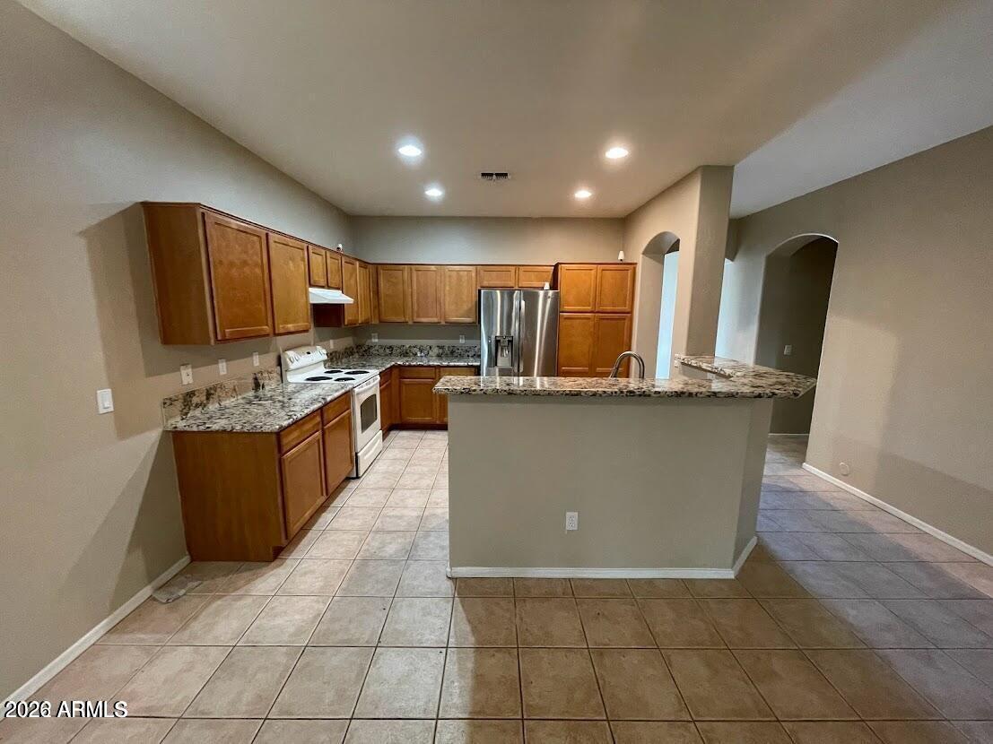 3095 East Merlot Street Gilbert, AZ 85298 - Photo 4 of 13 a kitchen with kitchen island granite countertop a stove a sink a refrigerator and a microwave