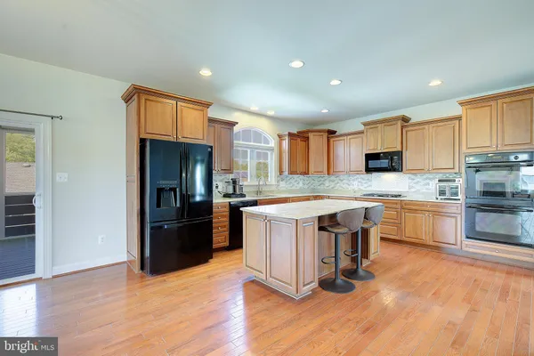 a kitchen with stainless steel appliances granite countertop a refrigerator a sink dishwasher a stove and oven with wooden floor