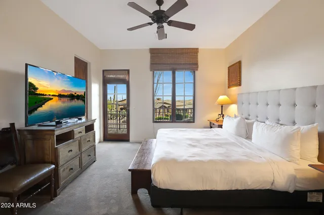 a spacious bedroom with a bed and a flat screen tv
