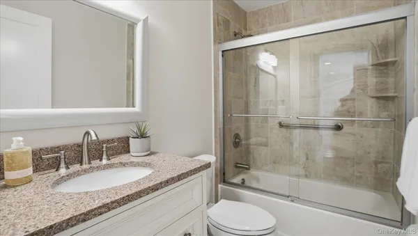 a bathroom with a granite countertop sink toilet and shower