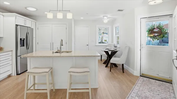 a kitchen with stainless steel appliances kitchen island granite countertop a table chairs in it and wooden floors