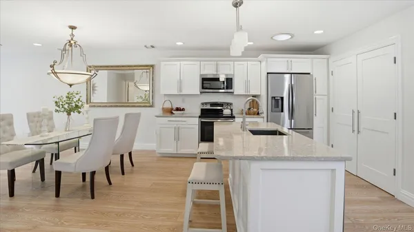 a kitchen with stainless steel appliances granite countertop a dining table chairs refrigerator and microwave