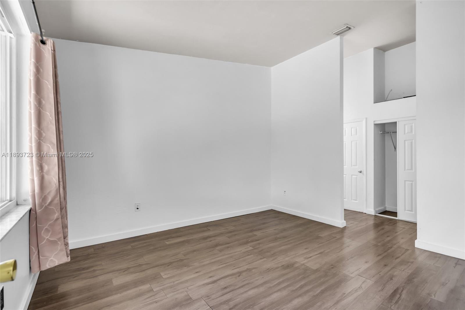 6713 Northwest 188th Terrace, Unit 6713 Hialeah, FL 33015 - Photo 14 of 28 a view of an empty room with wooden floor and a window