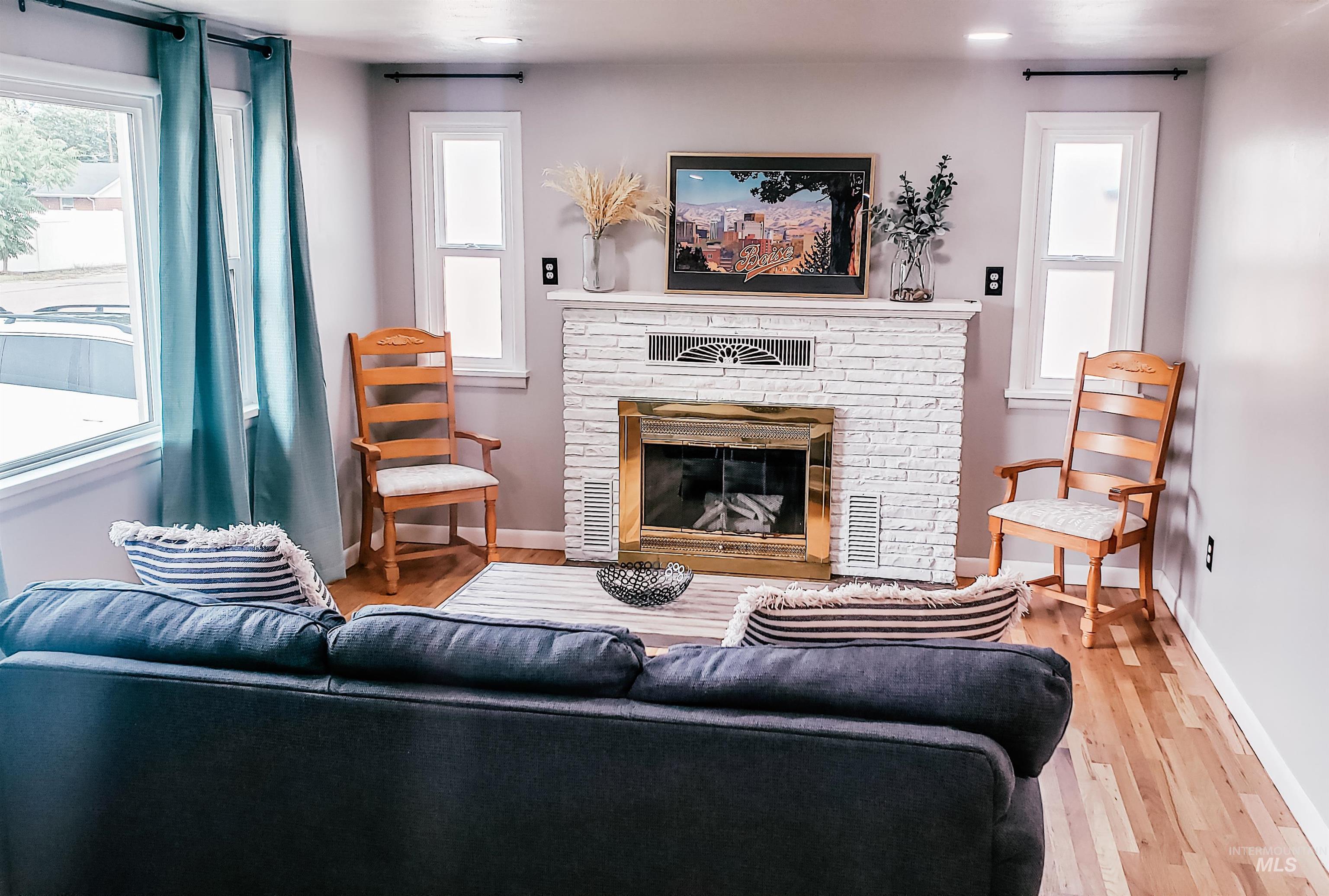 814 Baker Street Boise, ID 83706 - Photo 3 of 26 Living area featuring a white brick fireplace with a brass-trimmed insert, hardwood flooring, recessed lighting, and a dual-pane window