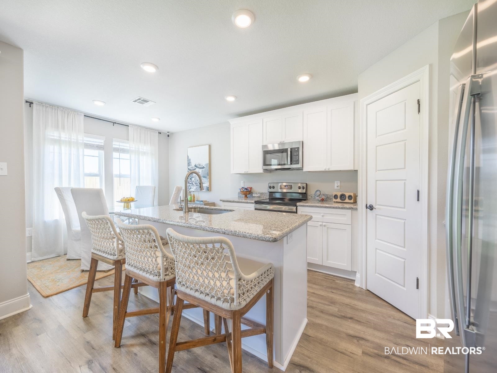 23911 Peppermint Street Elberta, AL 36530 - Photo 4 of 18 Kitchen featuring stainless steel appliances, light stone countertops, a kitchen island with sink, a kitchen bar, and white cabinetry
