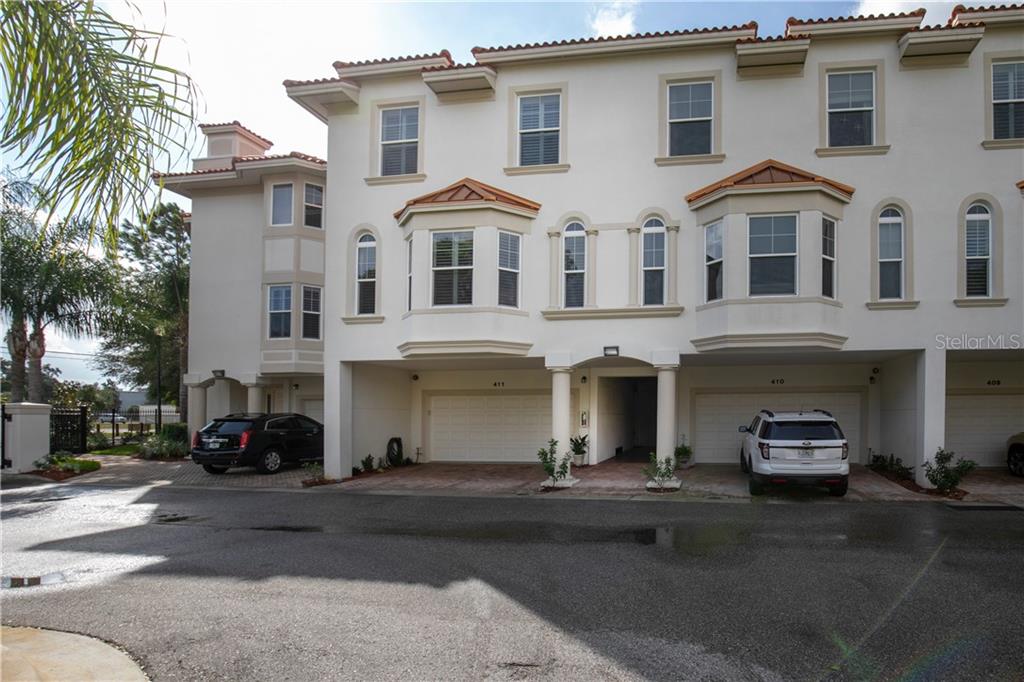 a front view of a building with lot of cars and trees