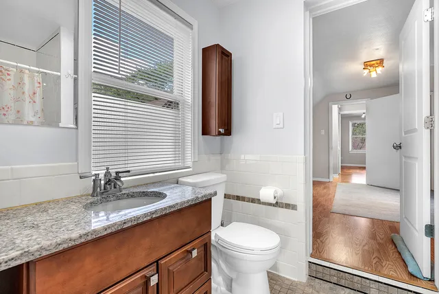a bathroom with a granite countertop sink a toilet a mirror and shower