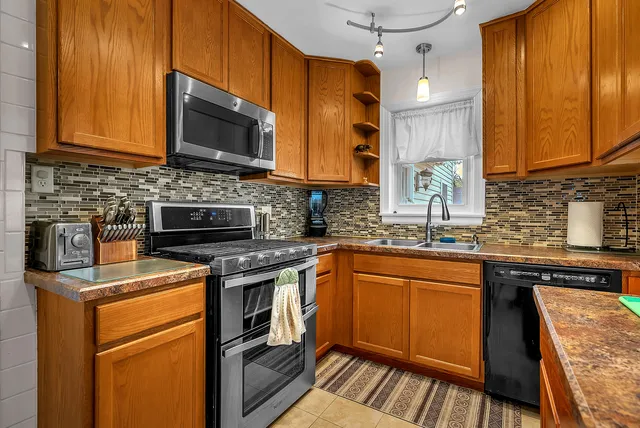 a kitchen with stainless steel appliances granite countertop wooden cabinets a stove top oven a sink and dishwasher
