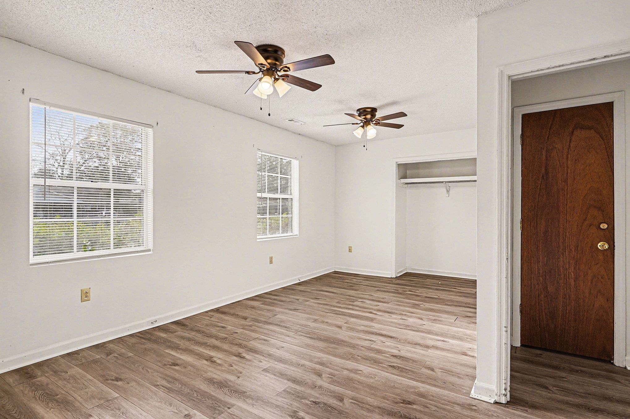 916 Brinkley Street Georgetown, SC 29440 - Photo 15 of 39 Unfurnished bedroom featuring a closet, ceiling fan, wood finished floors, multiple windows, and a textured ceiling