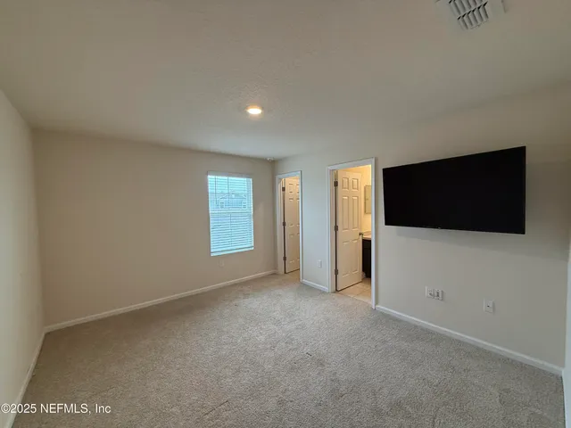 a view of an empty room with a window and a flat screen tv