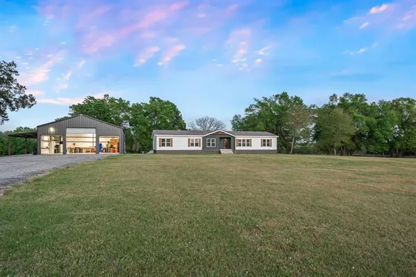 a view of a big house with a big yard and large trees