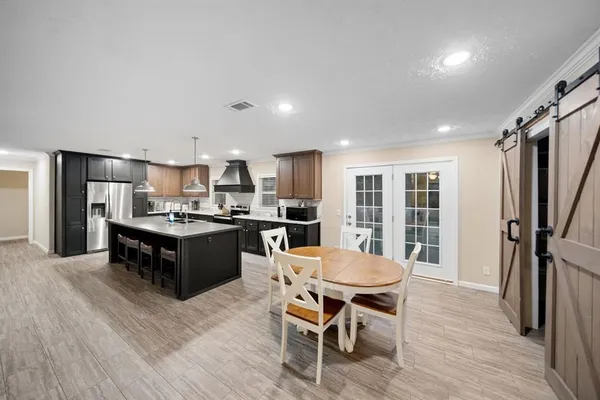 a kitchen with a table chairs refrigerator and wooden floor