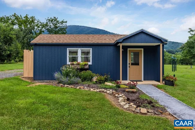 a view of backyard of house with wooden deck and large trees