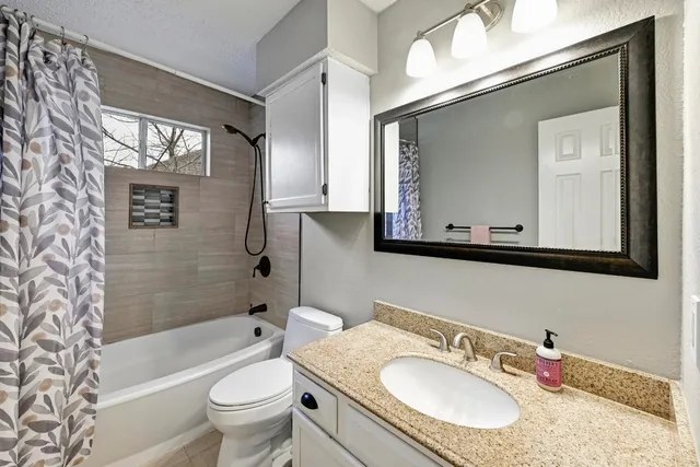 a bathroom with a granite countertop sink toilet mirror and bathtub
