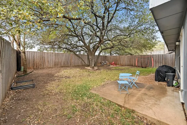 a view of backyard with table and chairs and wooden fence