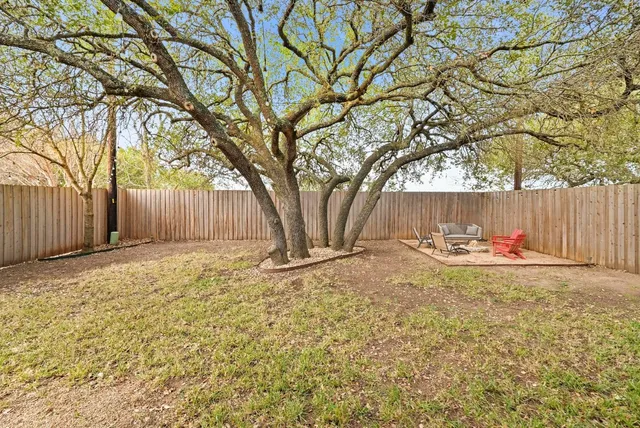 a view of a backyard with large trees and wooden fence