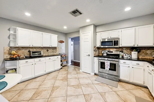 a kitchen with stainless steel appliances granite countertop a stove a sink and a microwave