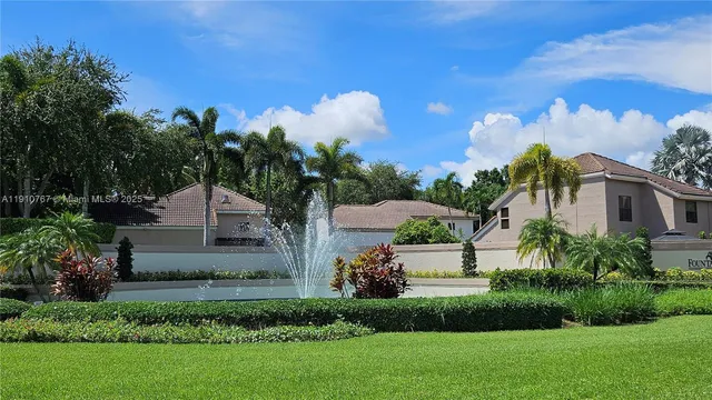 a front view of a house with a yard and a fountain
