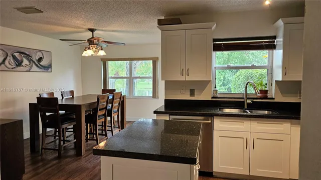 a kitchen with kitchen island granite countertop a sink cabinets and window