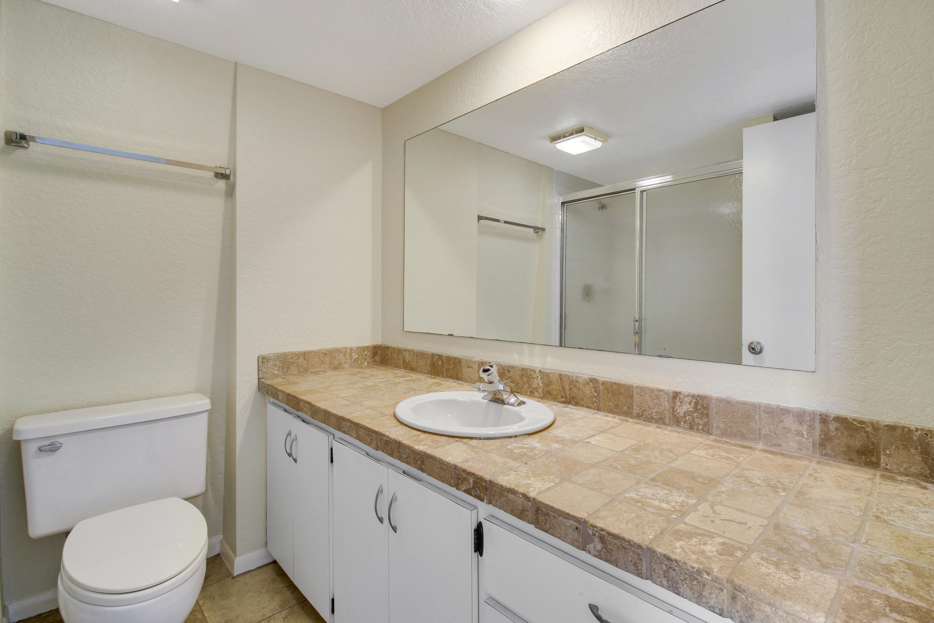 3900 County Line Road, Unit 21D Tequesta, FL 33469 - Photo 18 of 20 a bathroom with a granite countertop sink a toilet and a shower