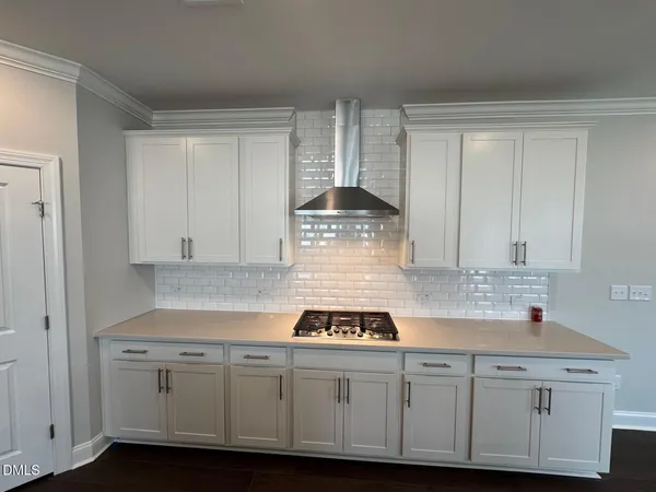 a kitchen with stainless steel appliances a stove a sink a refrigerator and white cabinets with wooden floor