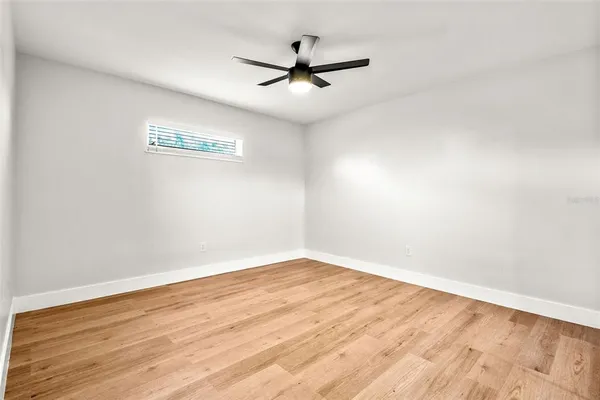 an empty room with wooden floor and ceiling fan