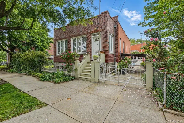 a view of a brick house with plants and large tree