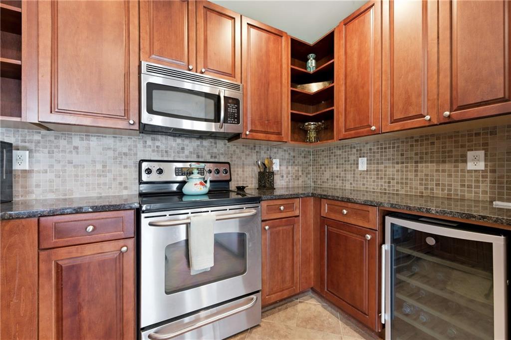 117 South Bay Road, Unit 402 Eatonton, GA 31024 - Photo 34 of 48 a kitchen with stainless steel appliances granite countertop wooden cabinets and a stove top oven