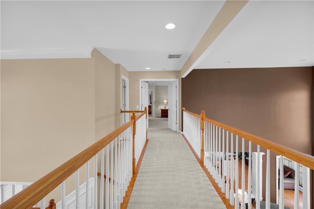 1709 Travers Road Breinigsville, PA 18031 - Photo 27 of 55 A well-lit second-story hallway featuring wooden railings and carpeted flooring, leading to additional rooms.