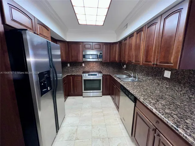 a large kitchen with stainless steel appliances granite countertop a refrigerator a stove and a sink