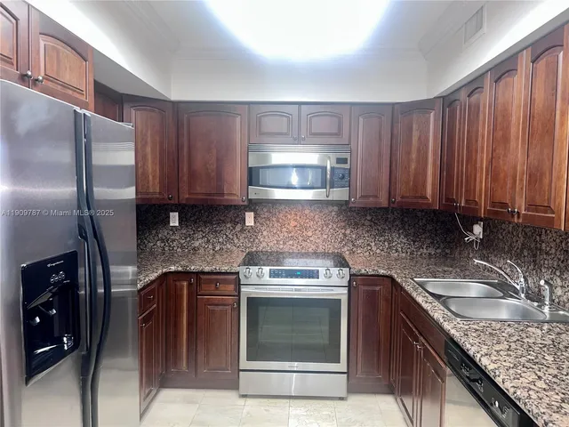 a kitchen with granite countertop a sink stove and refrigerator