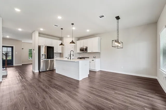 a view of kitchen with cabinets stainless steel appliances and wooden floor