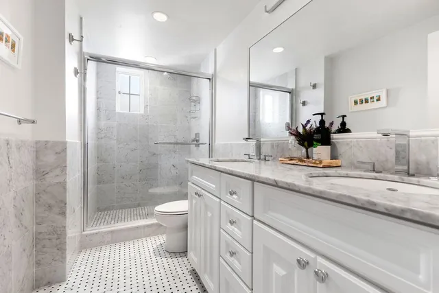a bathroom with a double vanity sink toilet and shower