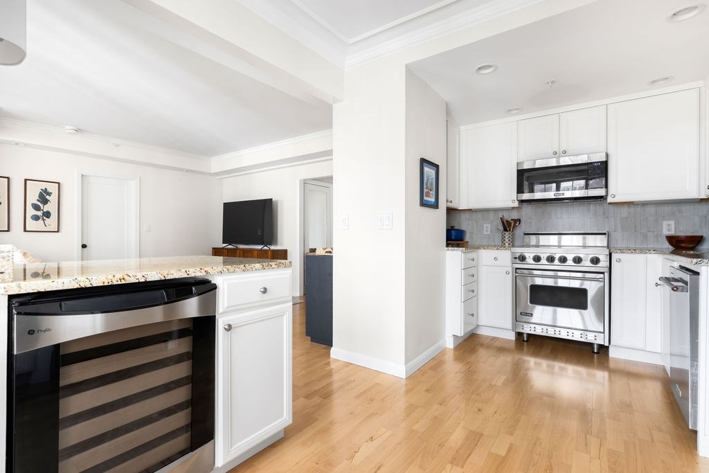 20 Chapel Street, Unit B712 Brookline, MA 02446 - Photo 6 of 25 a kitchen with stainless steel appliances a stove top oven a refrigerator white cabinets and wooden floor
