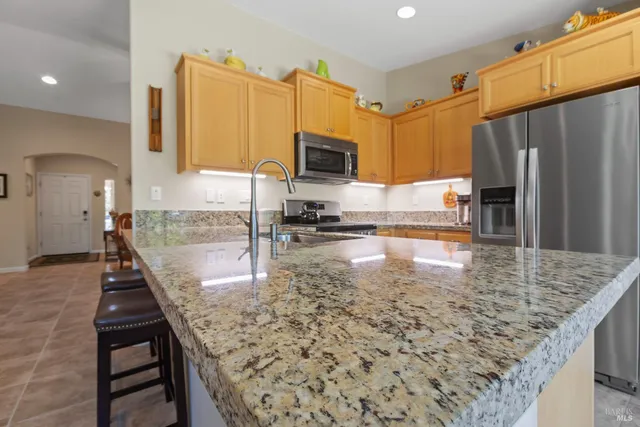 a kitchen with kitchen island granite countertop a stove a sink and a microwave