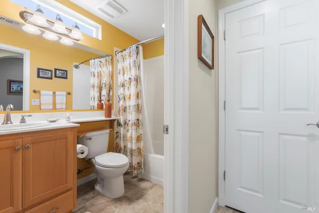 a bathroom with a granite countertop toilet a sink and a mirror