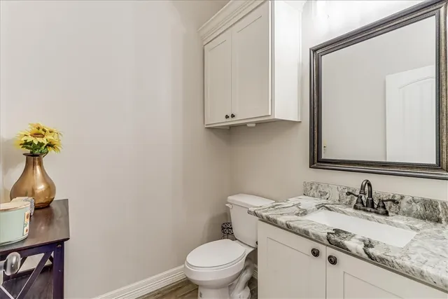 a bathroom with a granite countertop sink and a toilet