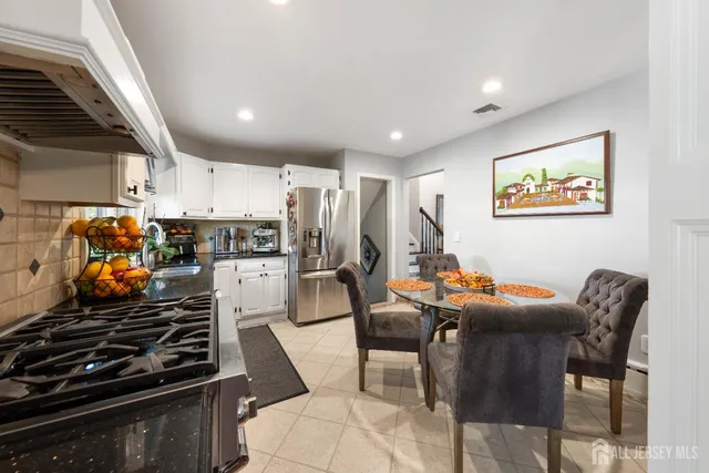 a kitchen with stainless steel appliances kitchen island granite countertop a stove a sink a refrigerator white cabinets and wooden floor