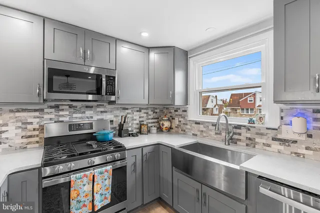 a kitchen with stainless steel appliances a sink a stove a microwave cabinets and a counter top space