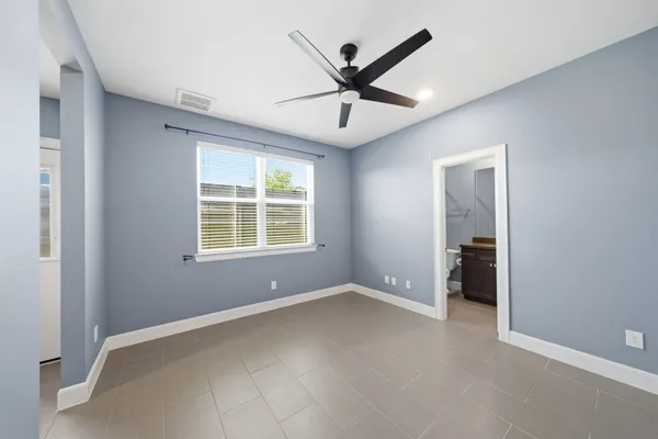 an empty room with ceiling fan and windows