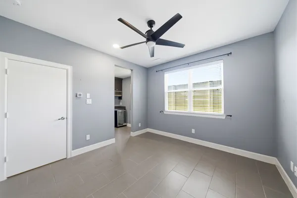an empty room with ceiling fan and windows