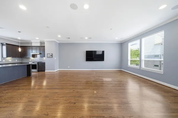 a living room with furniture kitchen view and a wooden floor