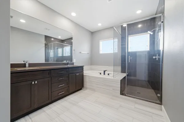 a spacious bathroom with a tub double sink shower and mirror