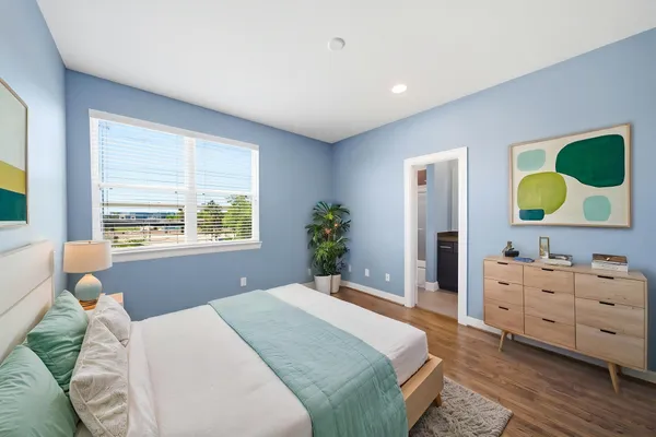 a bedroom with a bed mirror on dresser and a window